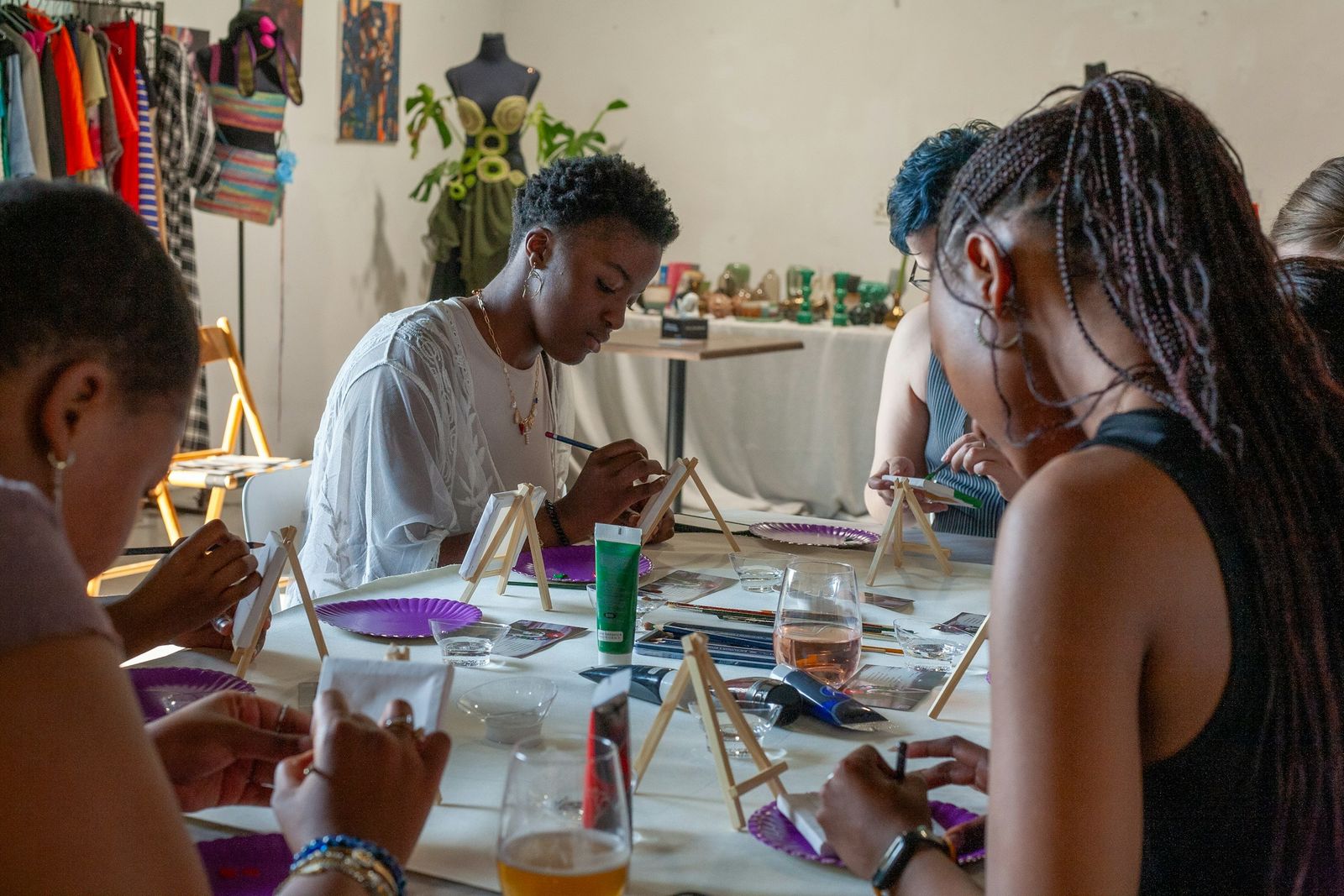 People gathered around a table painting small canvases propped on easels