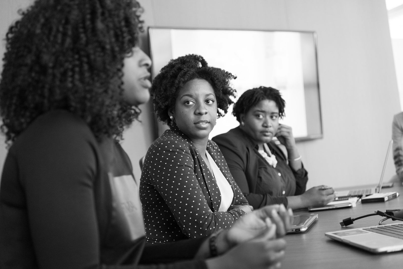 Women in discussion around a conference table, shown in black and white